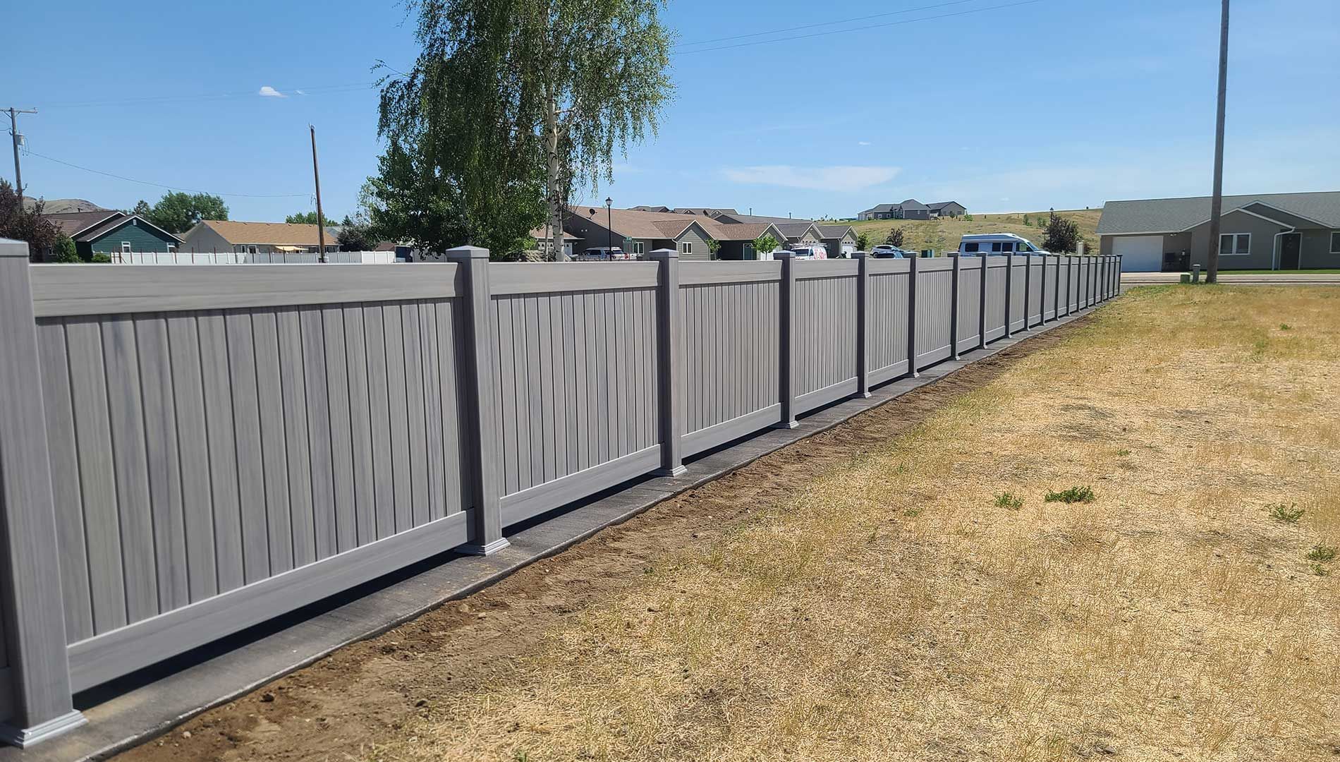 A gray fence is sitting in the middle of a grassy field.
