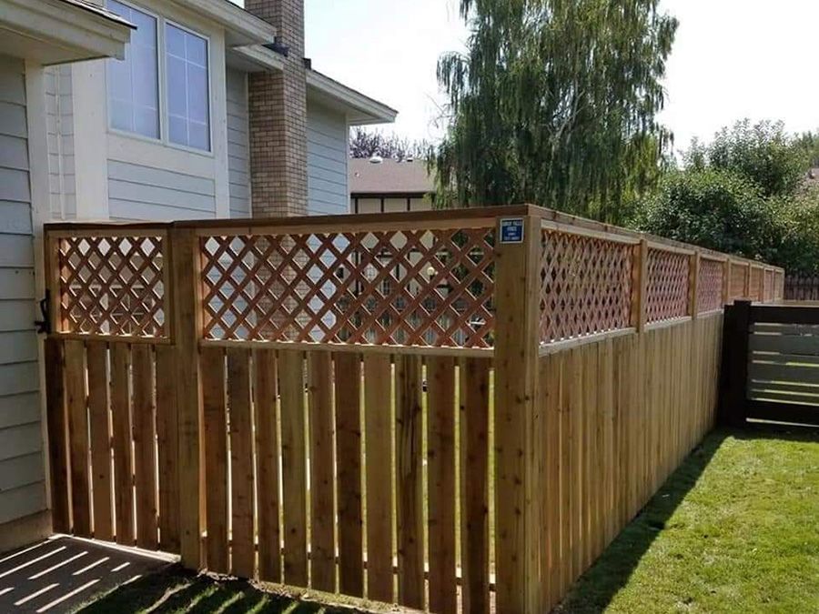 A wooden fence with a lattice on it is in front of a house.