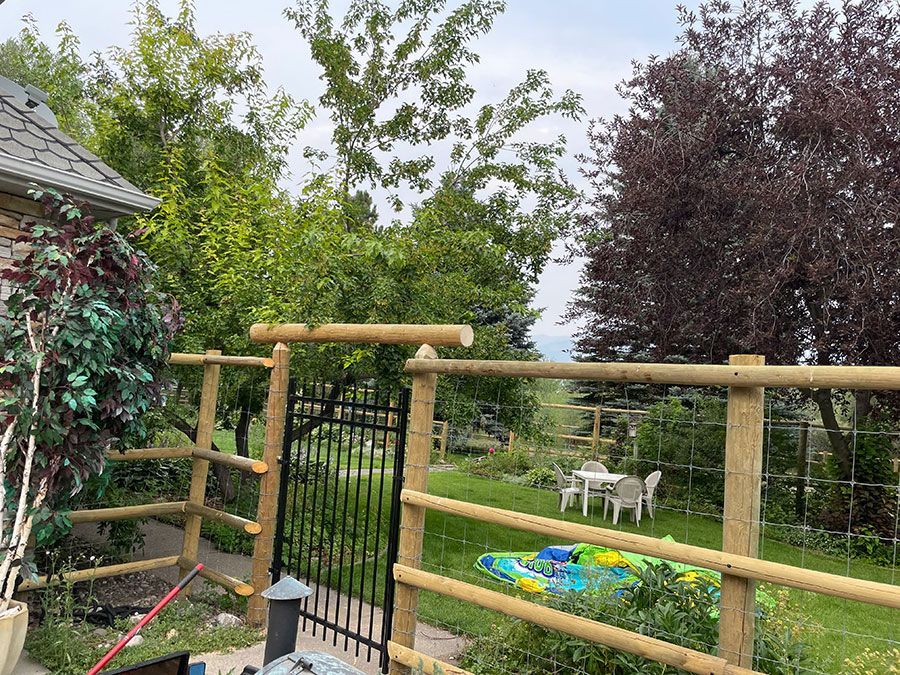 A wooden fence with a gate and a kayak in the backyard.
