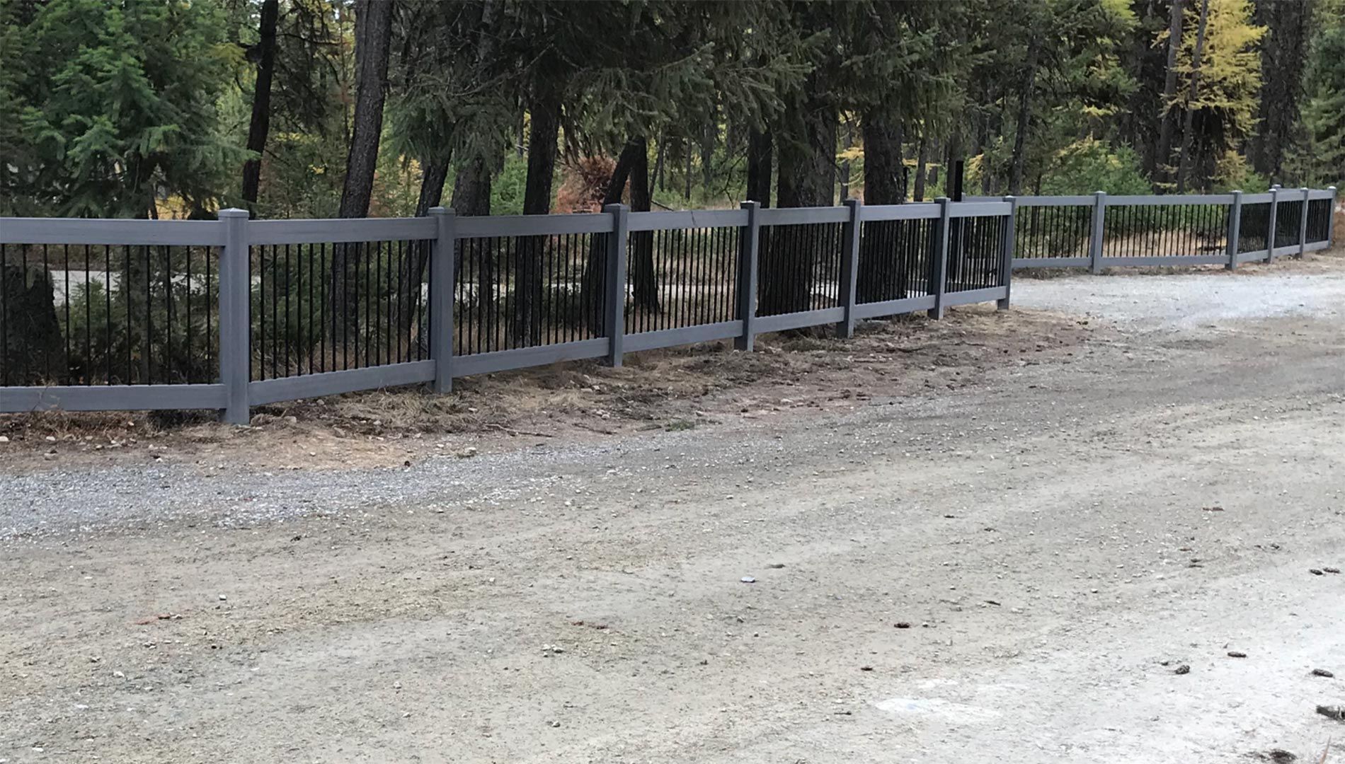 A gravel road with a fence along the side of it