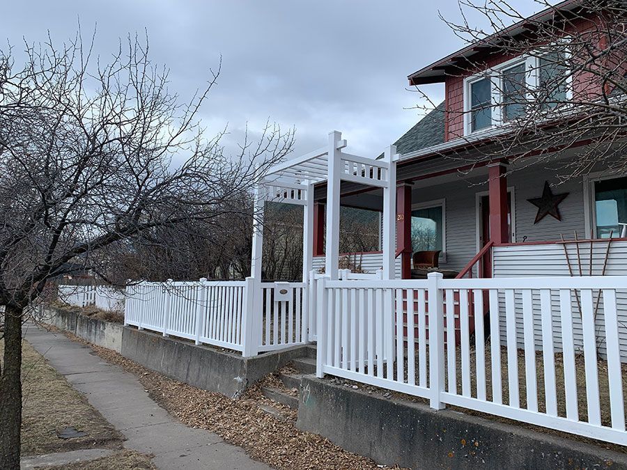 A white fence surrounds a red house with a porch.