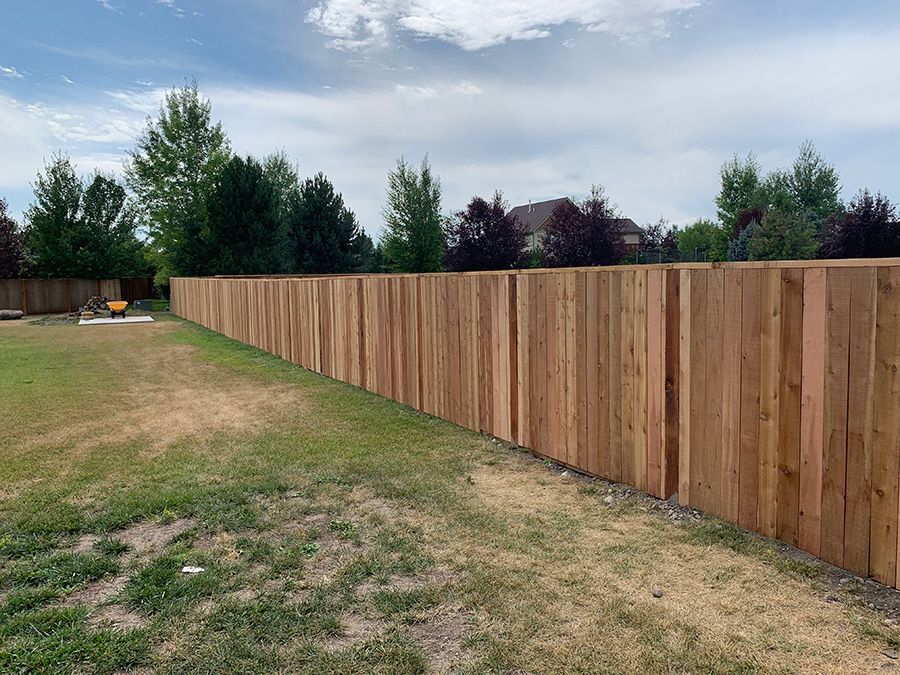 A long wooden fence surrounds a lush green field.