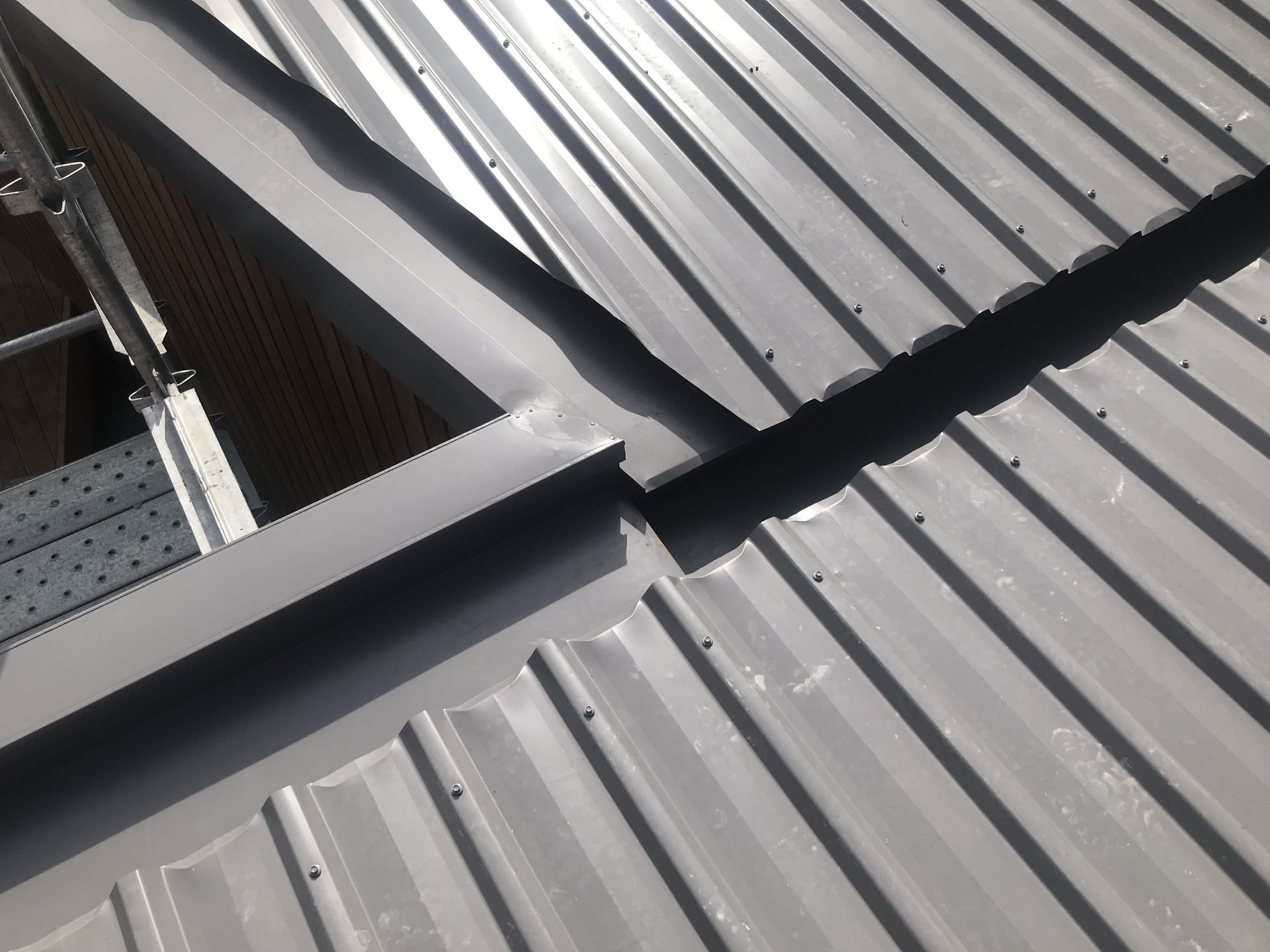Grey metal roof with a skylight, showing overlapping metal sheets and sealed seams. — R&M Sheetmetal Nowra Metal Roofing in South Nowra, NSW