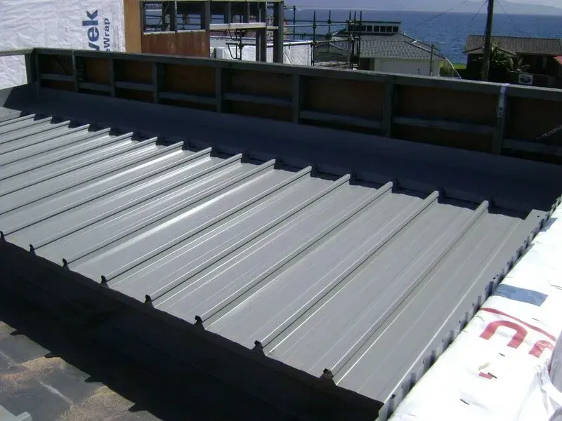 A Gray Metal Roof Is Being Installed on A Building A Gray Metal Roofing — R&M Sheetmetal Nowra Metal Roofing in South Nowra, NSW