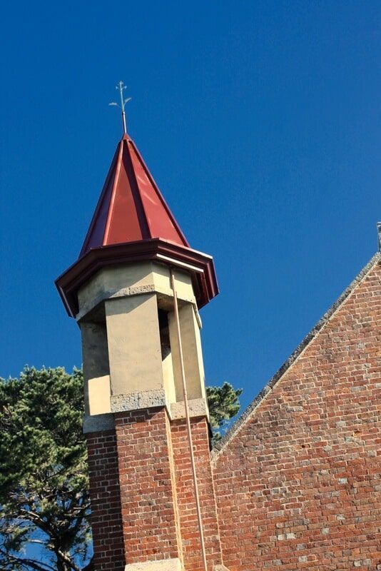A Church Tower with A Red Roof and A Cross on Top — R&M Sheetmetal Nowra Metal Roofing in South Nowra, NSW