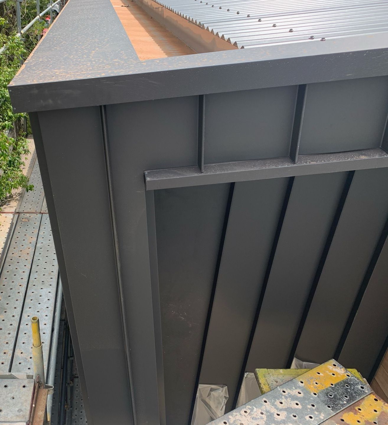 A black building with a roof and a ladder on the side of it. — R&M Sheetmetal Nowra Metal Roofing in Culburra, NSW