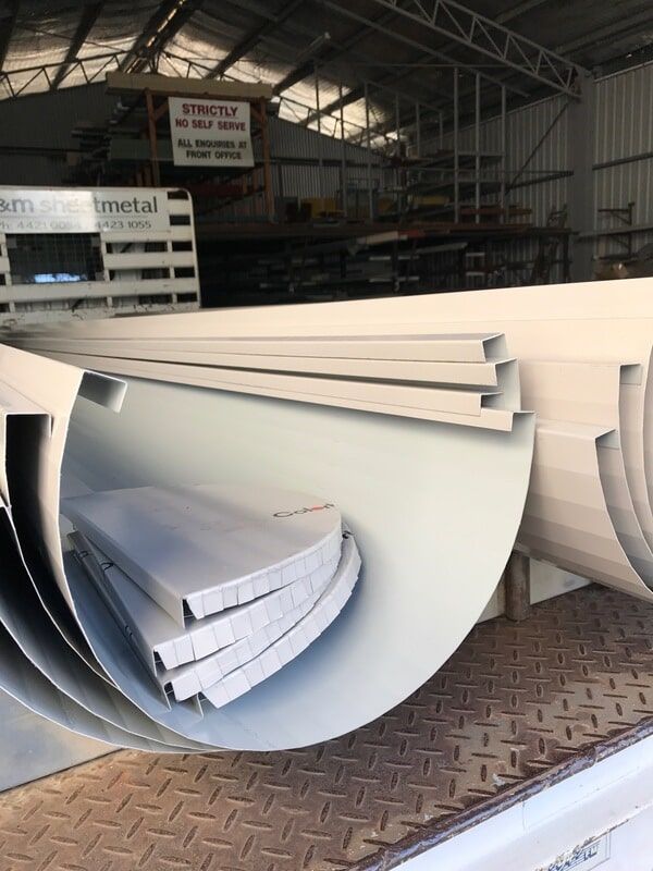A Stack of Gutters Sitting on Top of Each Other in A Warehouse — R&M Sheetmetal Nowra Metal Roofing in South Nowra, NSW