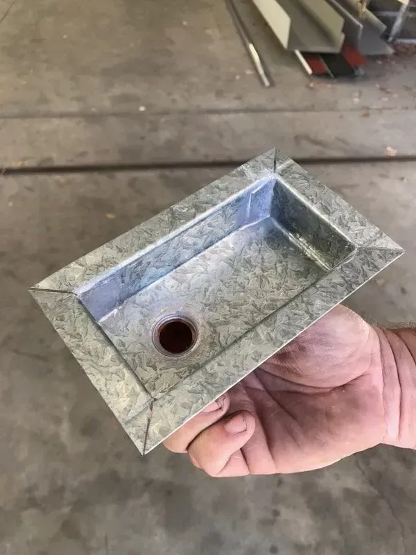 Hand holding a small, rectangular, metal sink basin with a drain hole. — R&M Sheetmetal Nowra Metal Roofing in South Nowra, NSW