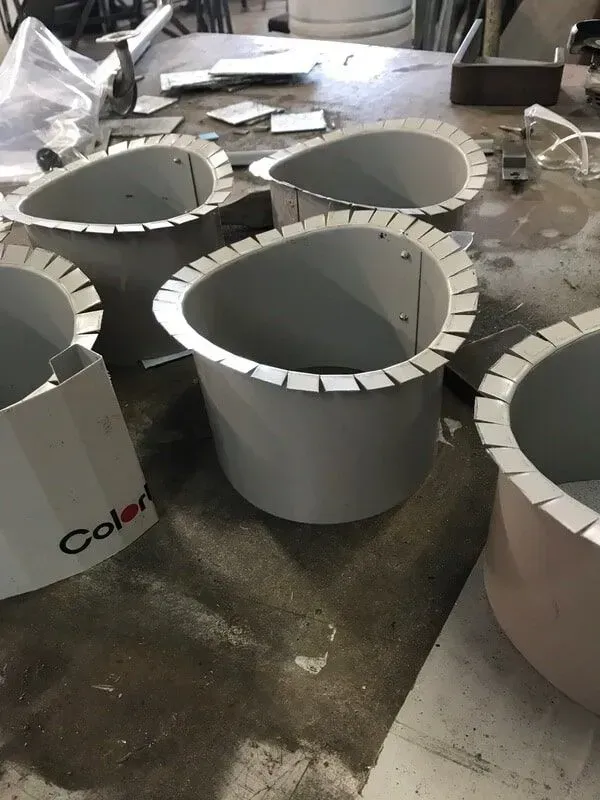 Grey metal cylinders with scalloped rims on a work surface, one with