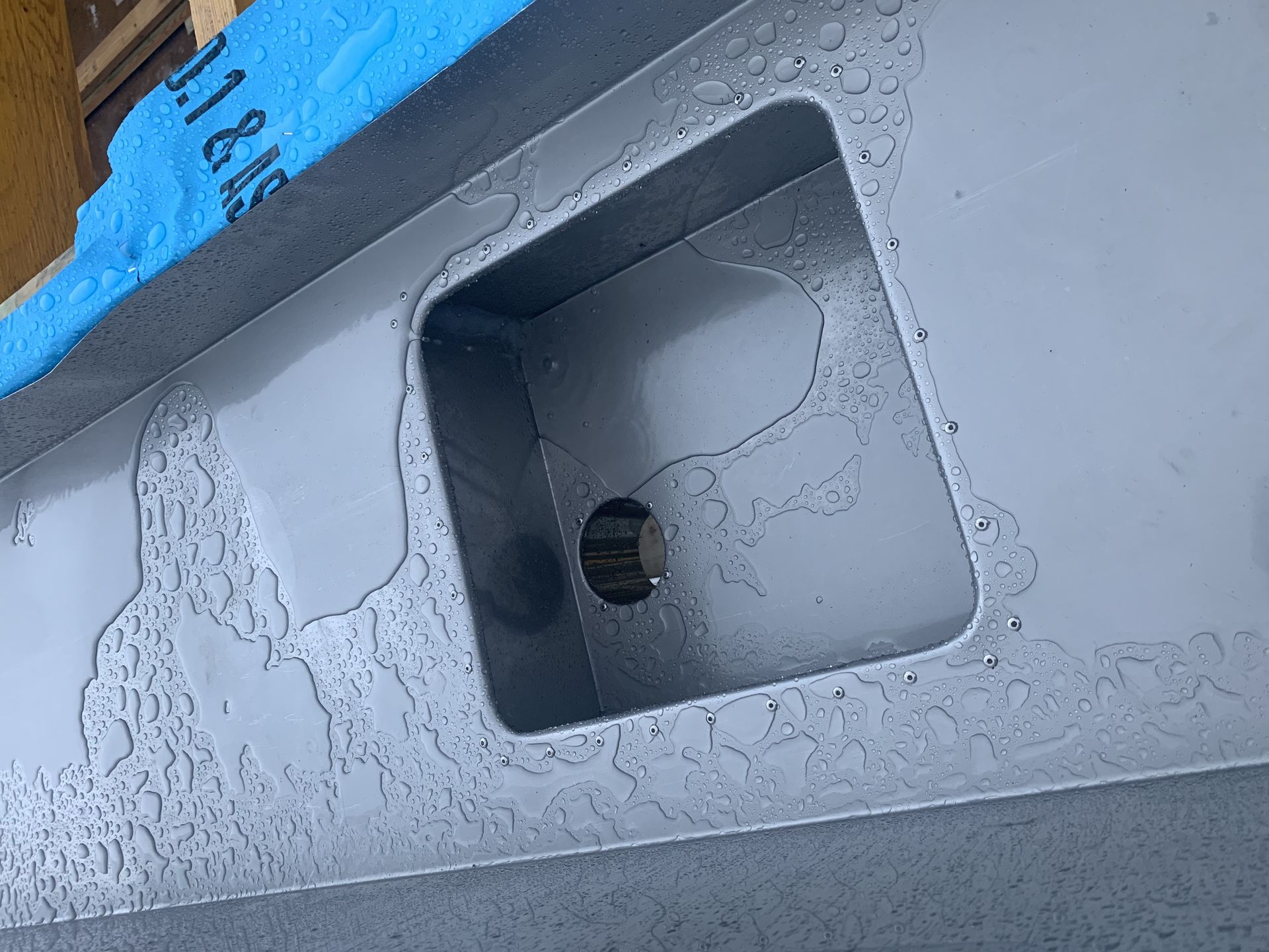 Grey metal surface with a rectangular cutout and circular hole. Water droplets are visible. — R&M Sheetmetal Nowra Metal Roofing in South Nowra, NSW