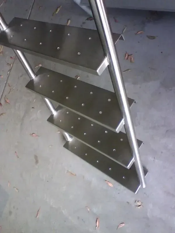 Stainless steel staircase with four steps, angled against a grey concrete floor. — R&M Sheetmetal Nowra Metal Roofing in South Nowra, NSW
