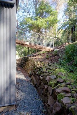 A Stone Wall with Moss on It Is Next to A Building — R&M Sheetmetal Nowra Metal Roofing in South Nowra, NSW