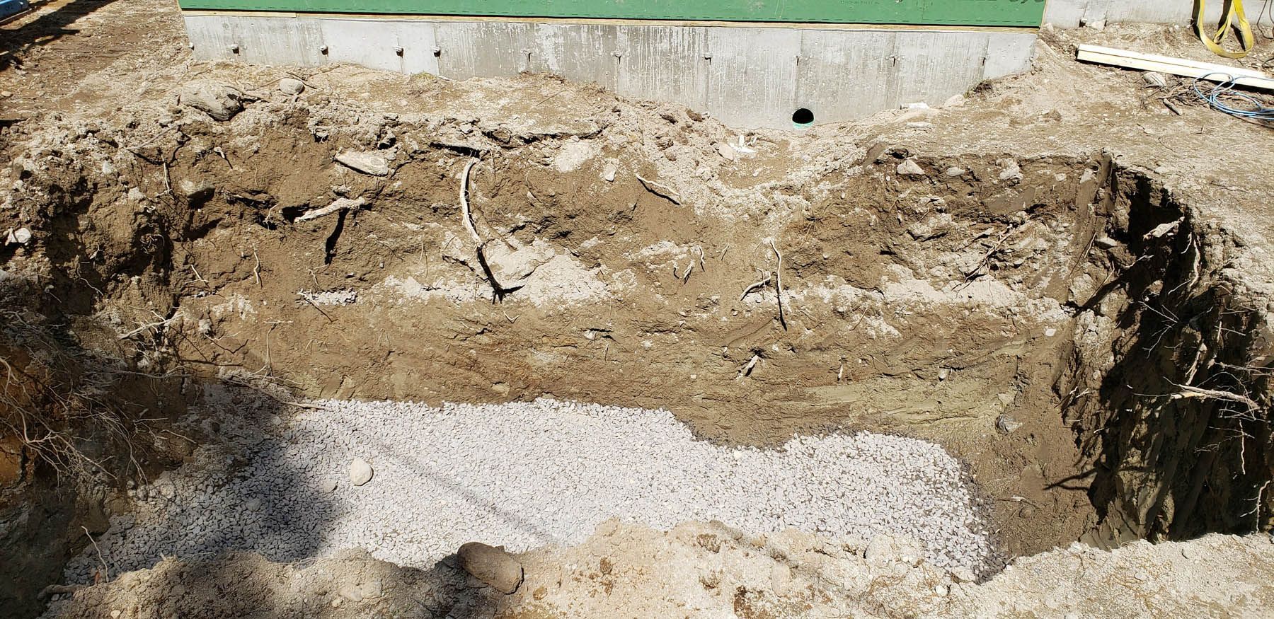 Excavated area with exposed earth and gravel beneath a concrete border.