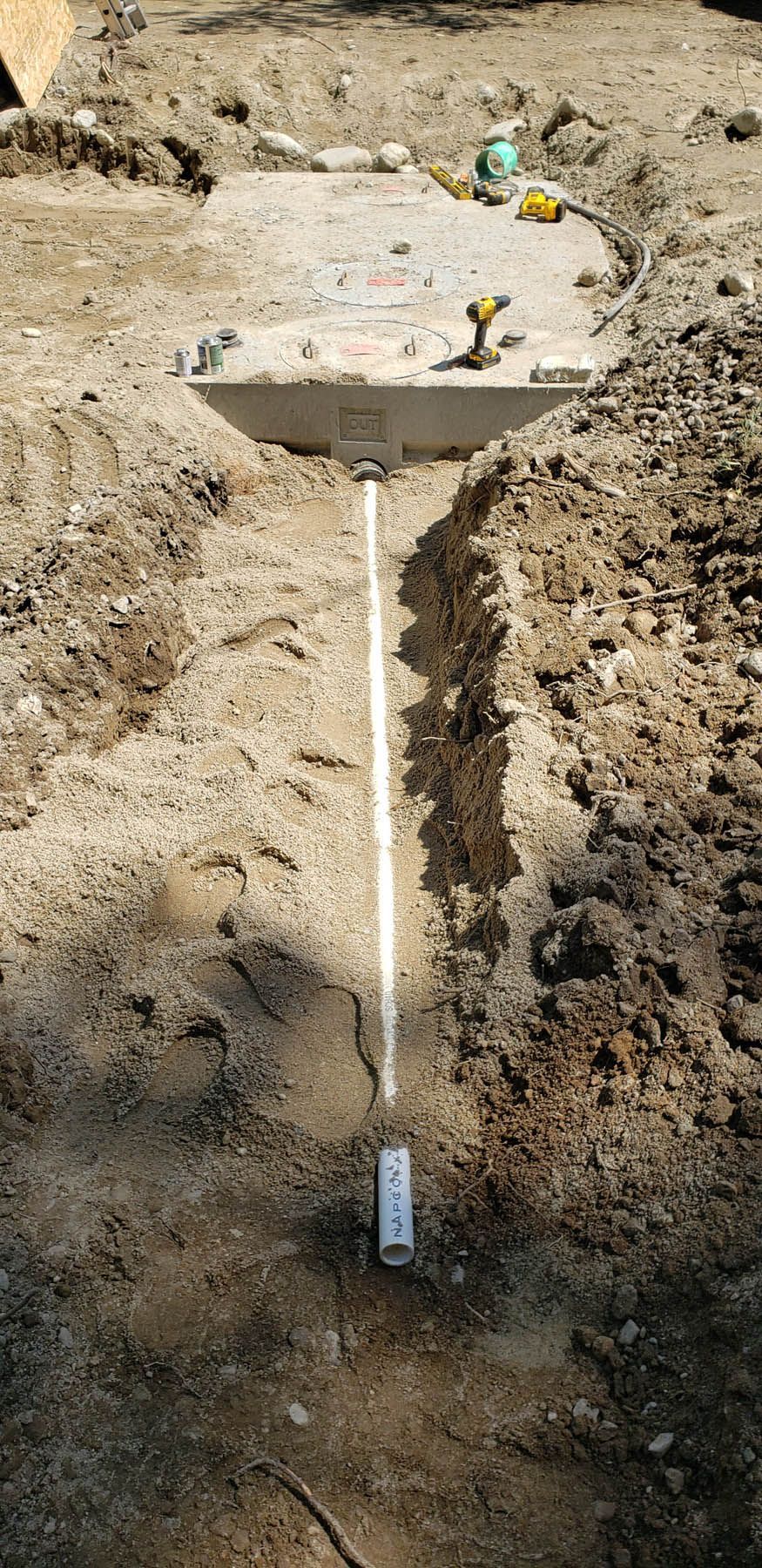A trench dug in the ground with a concrete slab and a white line running through the trench.