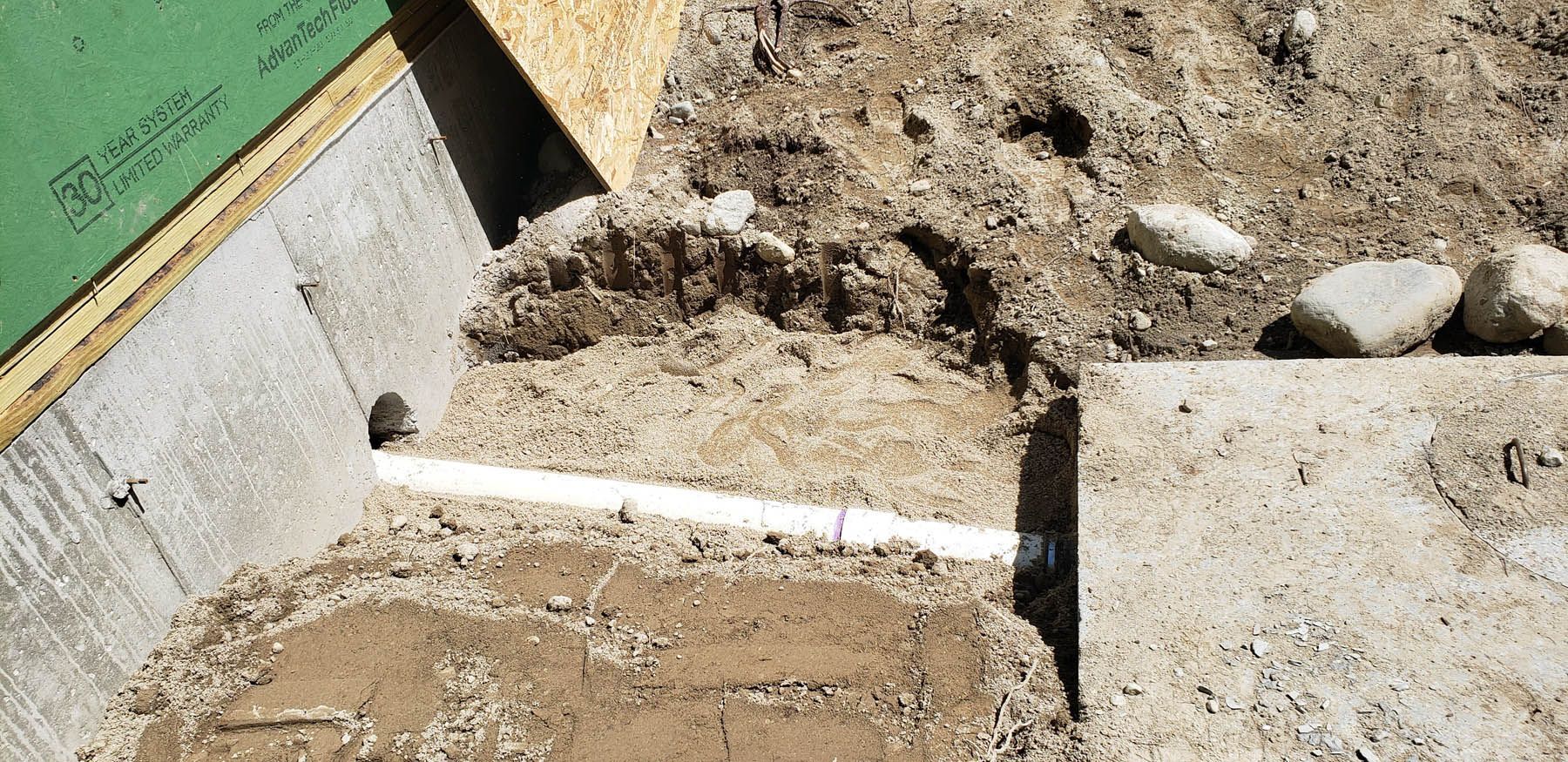 Concrete foundation with a white pipe and dirt.