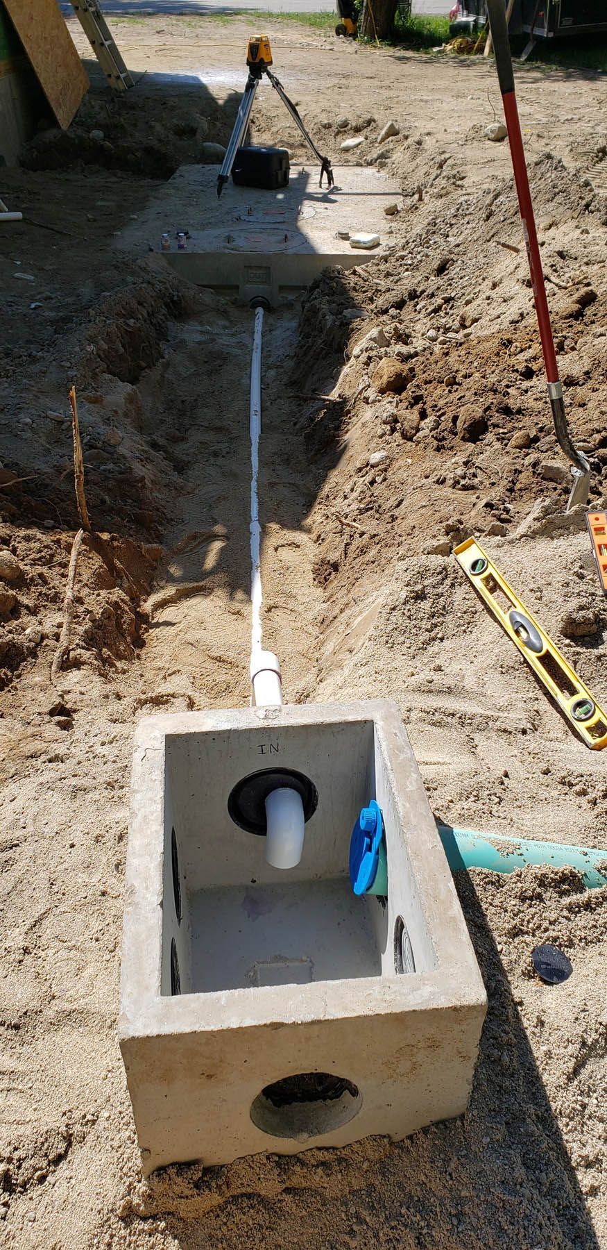 Construction site with concrete box, PVC pipe, and laser level.