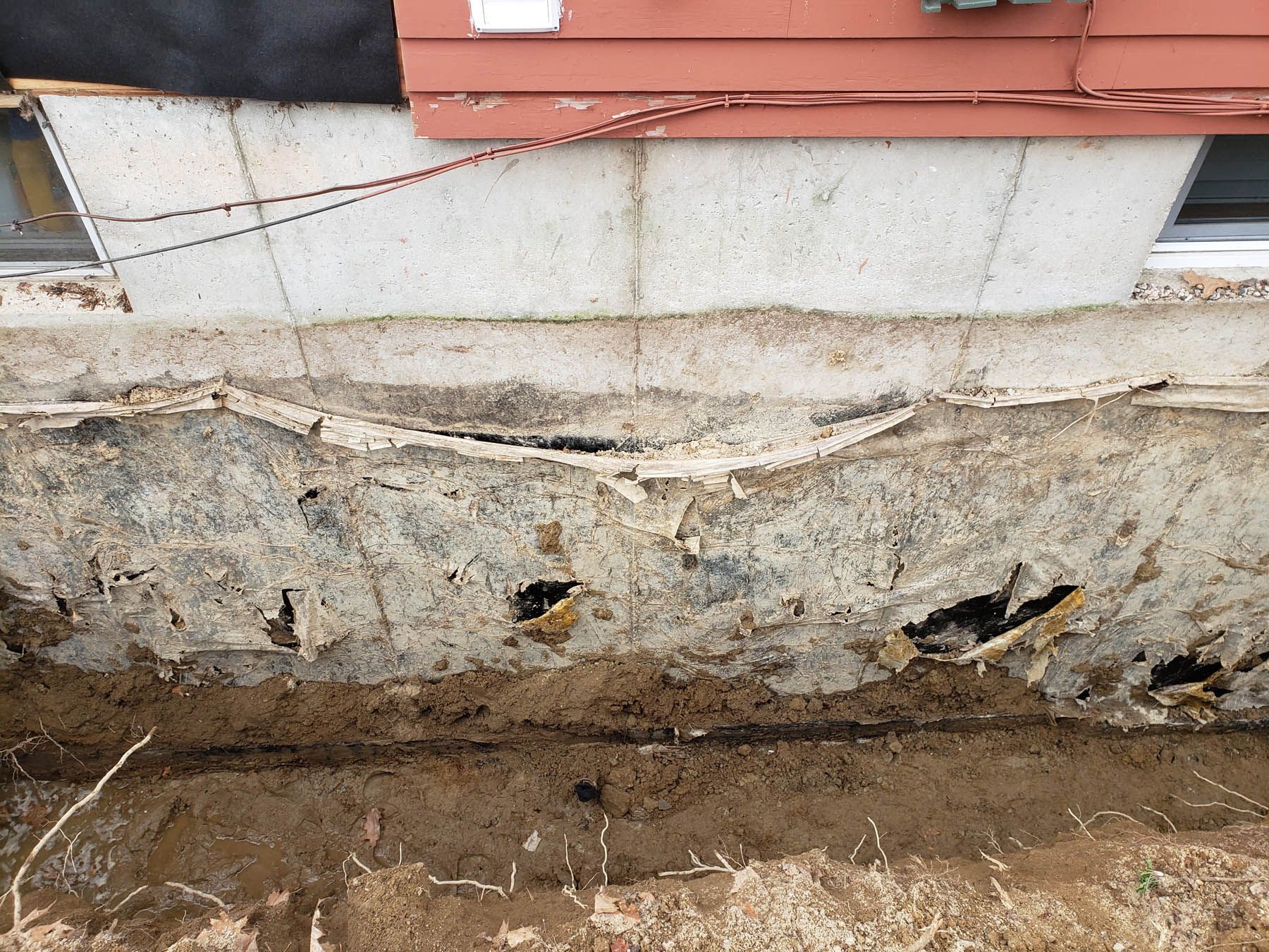 Damaged exterior house siding with visible holes, peeling, and underlying structure.