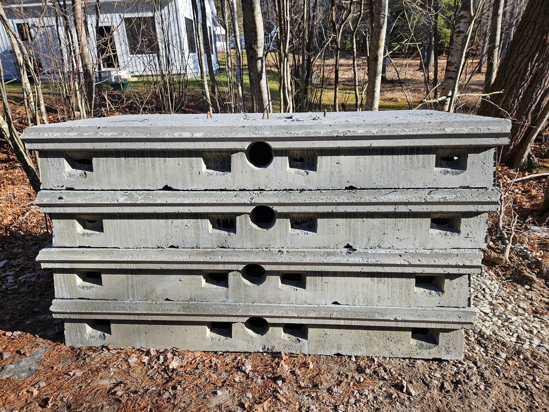 Stacked gray concrete blocks with holes, outdoors.