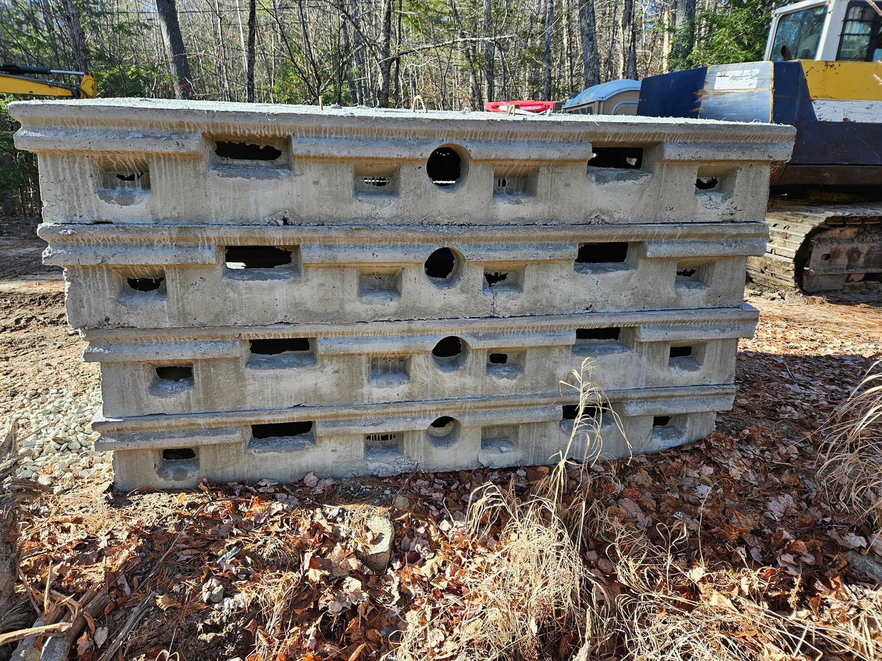 Stacked, gray concrete blocks with rectangular and circular openings, outdoors.
