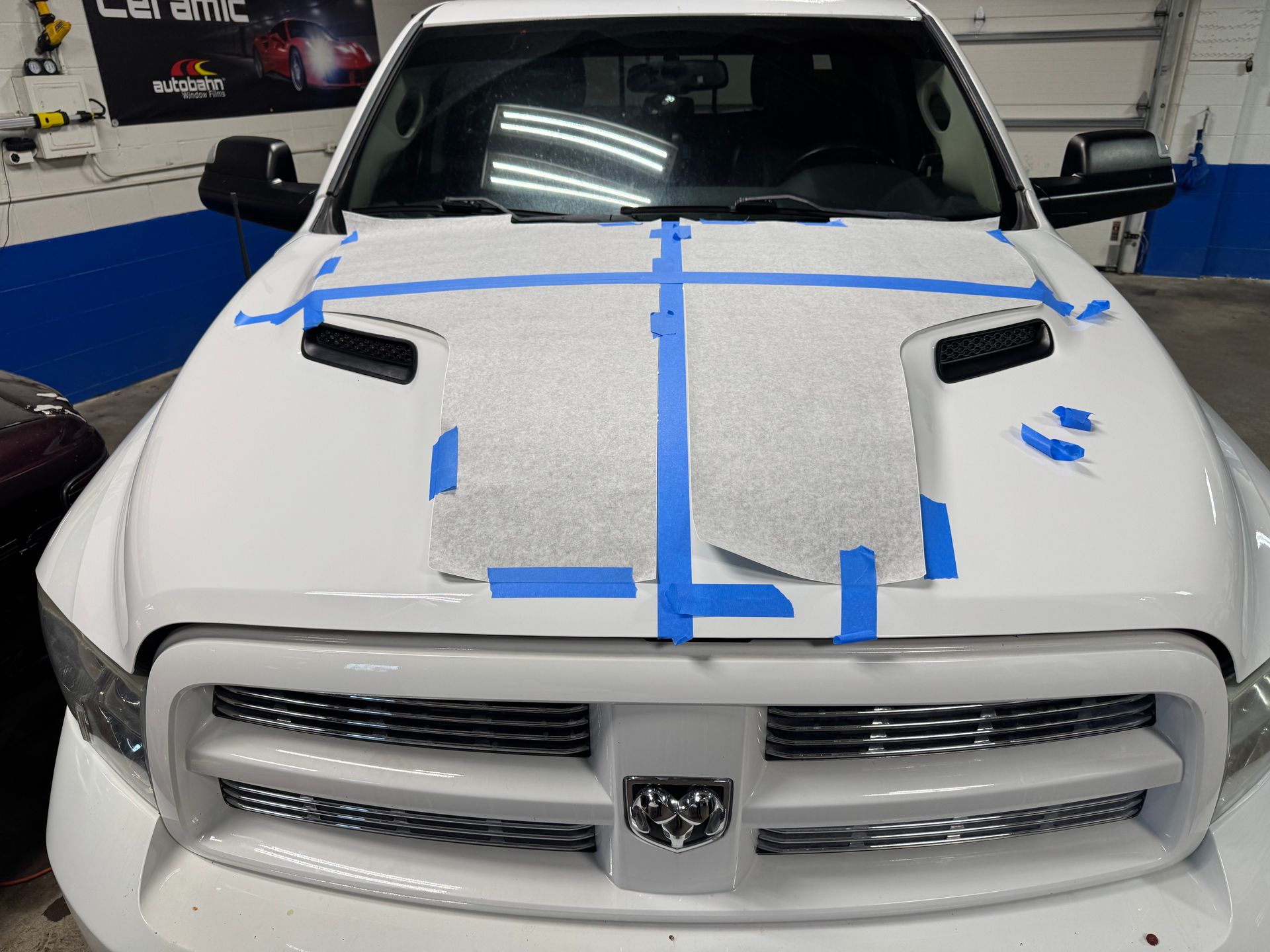 White truck hood with masking tape, possibly for detailing or paintwork.