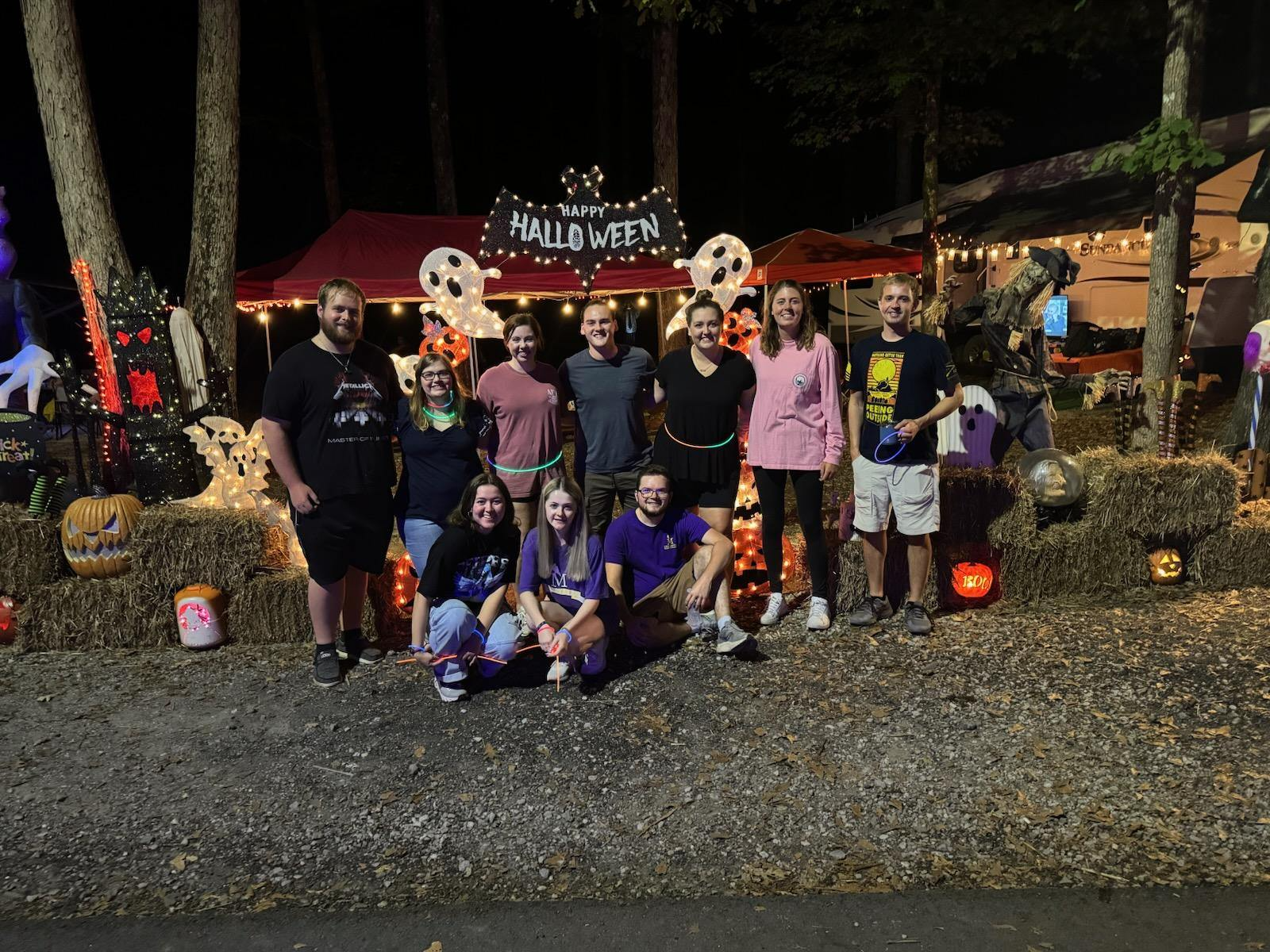 A group of people are posing for a picture in front of a halloween sign.