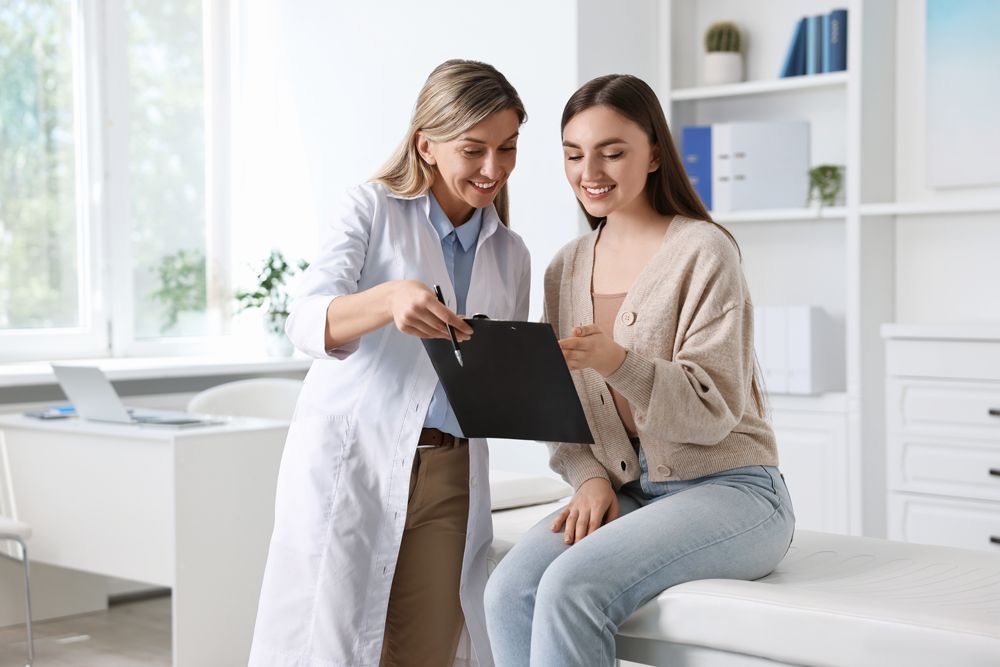 A doctor is talking to a patient who is sitting on a bed.
