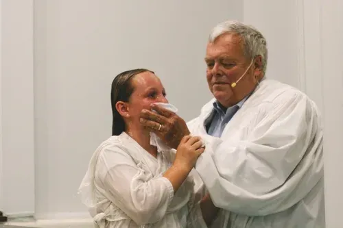 Two people in white coats smiling and embracing in a clinical setting