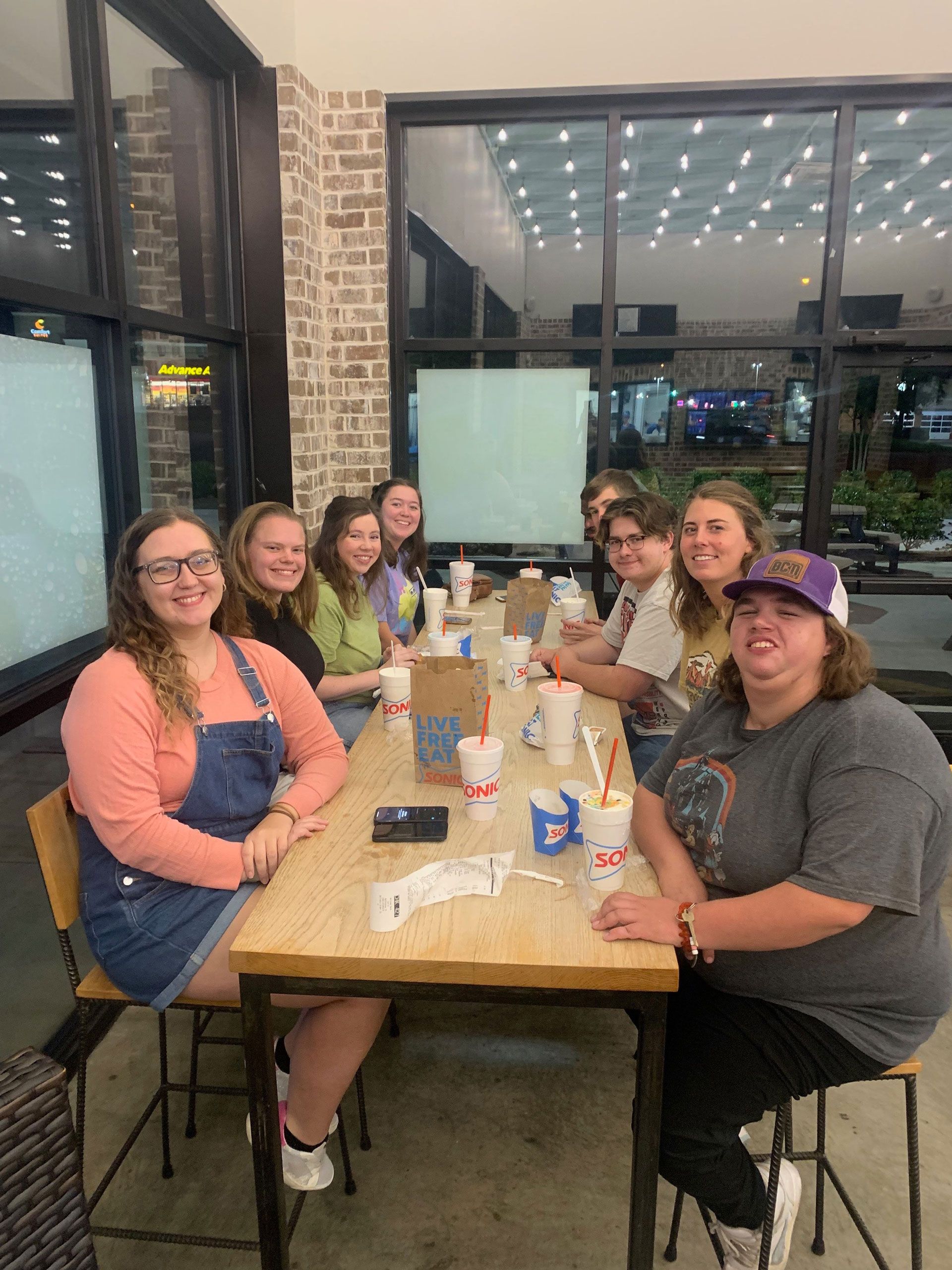 Group of friends seated at a restaurant table, smiling and posing for a photo.