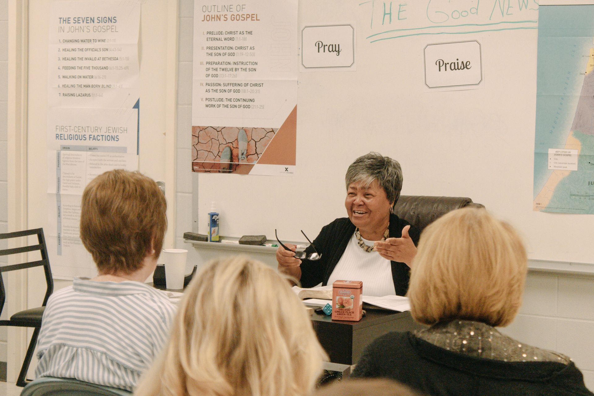 A woman sits at a desk in front of a white board with the word frog on it