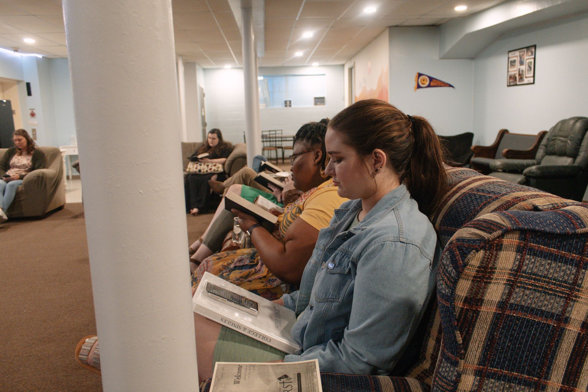 A group of women are sitting on a couch reading books.