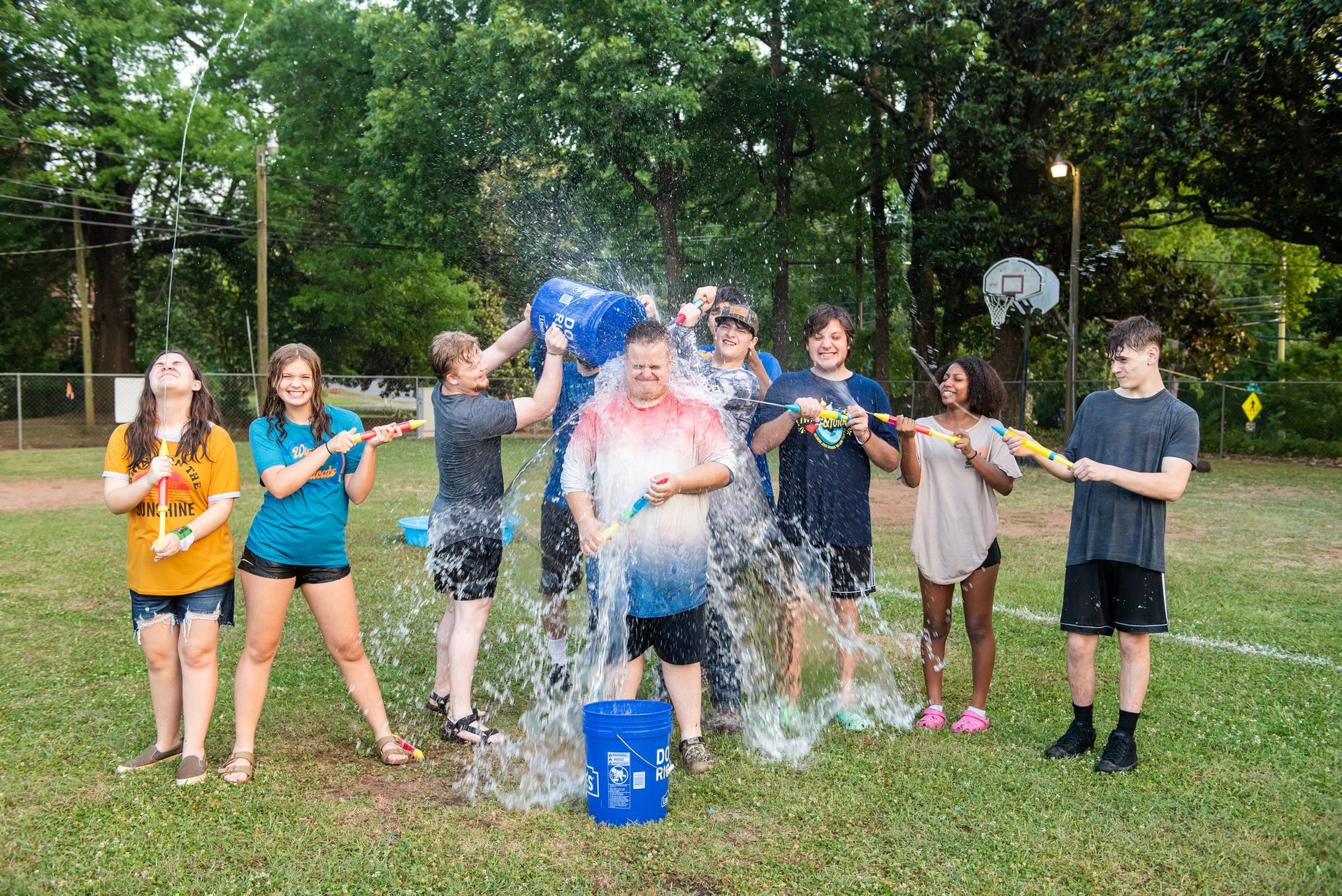 A group of young people are standing in a field with buckets of water.