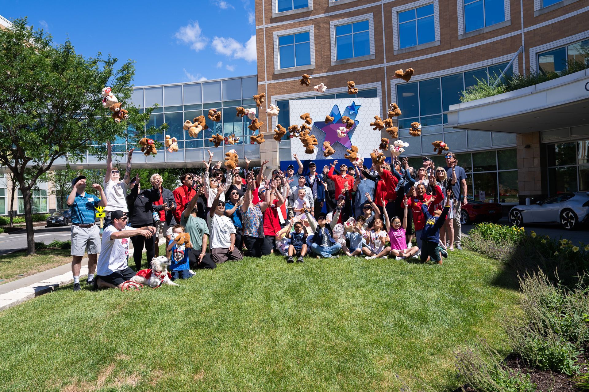 Ferrari Fun Day 2026 volunteers, families, and Children’s Hospital Association of Saint Paul supporters gather outside Children’s Minnesota in Saint Paul, Minnesota, tossing teddy bears to celebrate community support for pediatric patients and families.