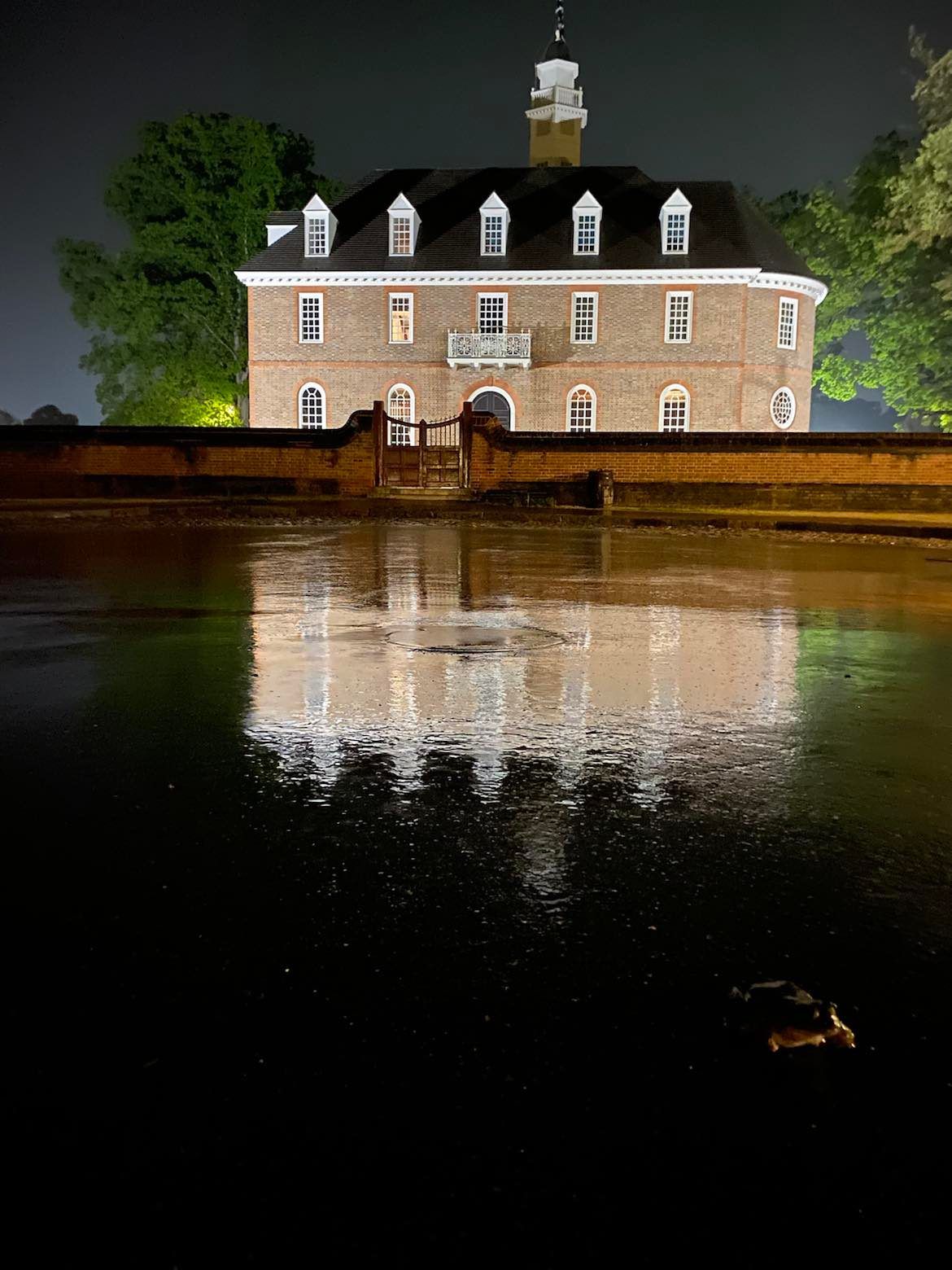 Brick building reflected in water at night.