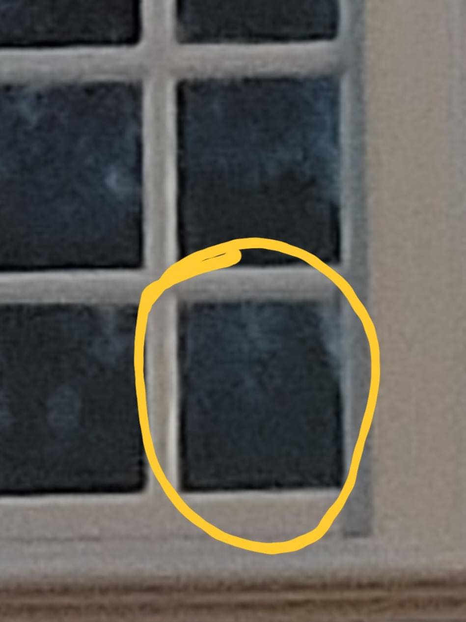A square window pane, highlighted in yellow, filled with a hazy, dark blue view.
