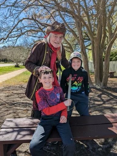 Pirate with two children outside, one holding a sword. Smiling.