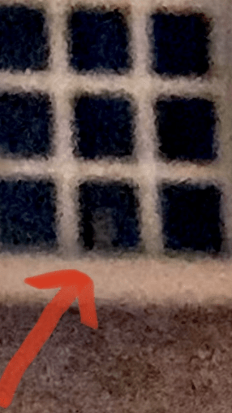 Close-up of a blue and white patterned surface, with an orange arrow pointing to the bottom edge.