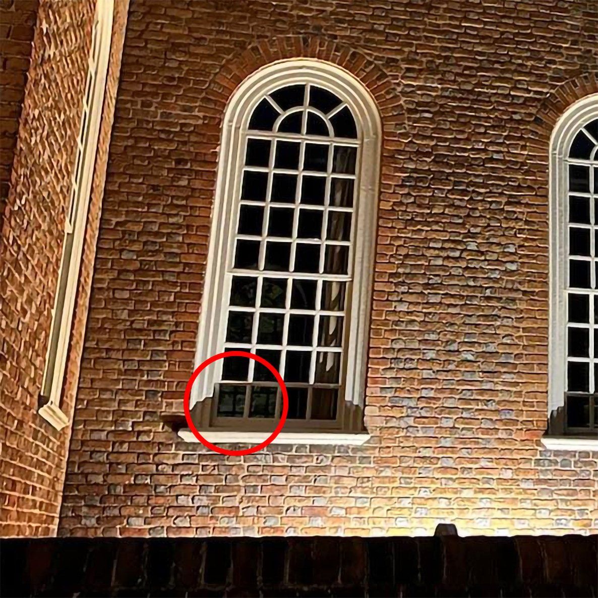 Red brick building with arched windows, one circled to highlight a lower window.