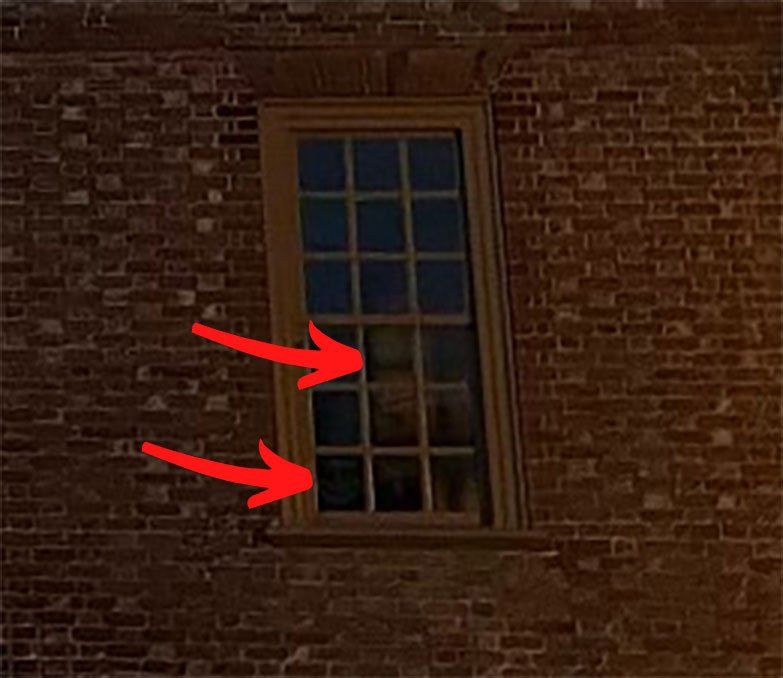 Brick building with a rectangular window; red arrows point to window panes.