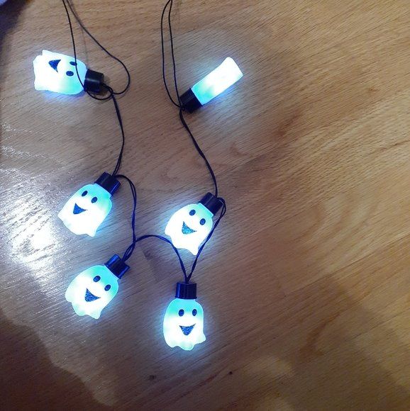 String of glowing blue Halloween ghost lights on a wooden surface.