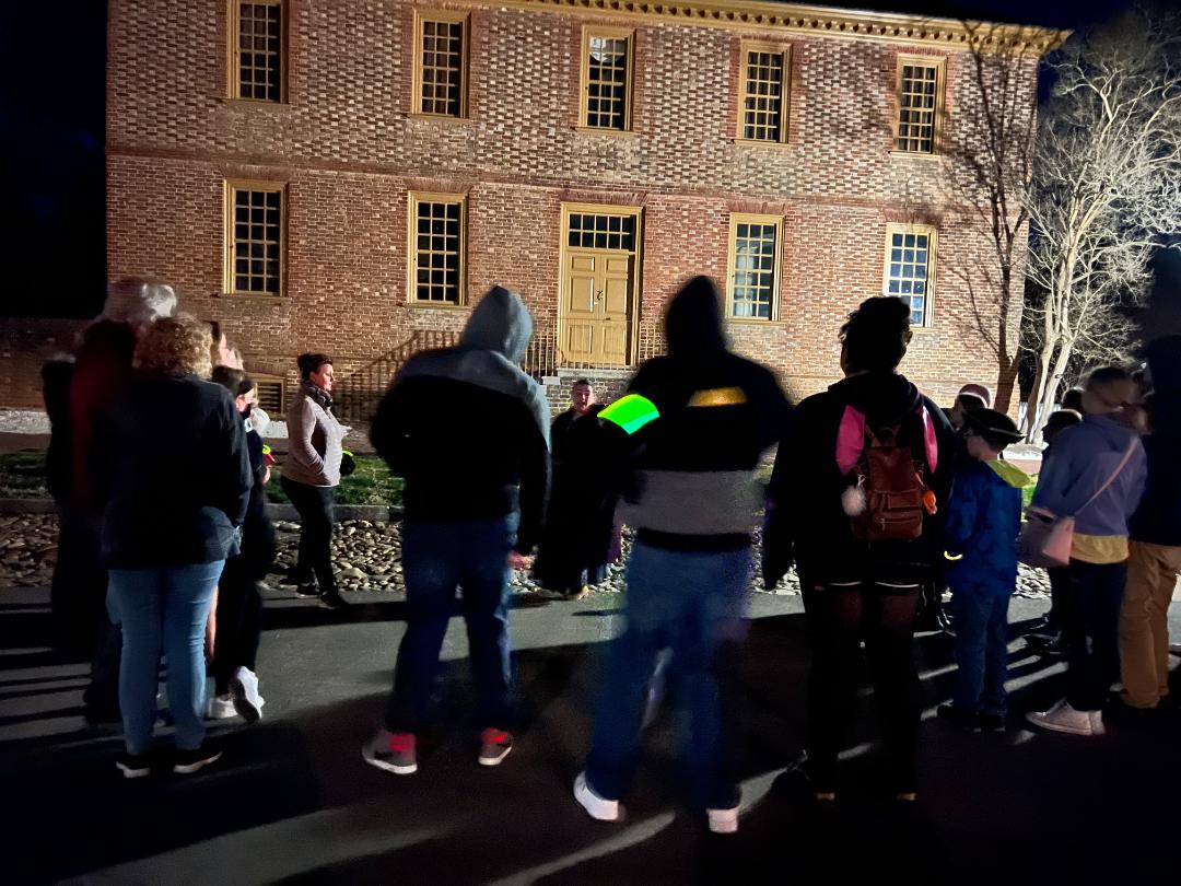 People gather in front of a brick building at night.