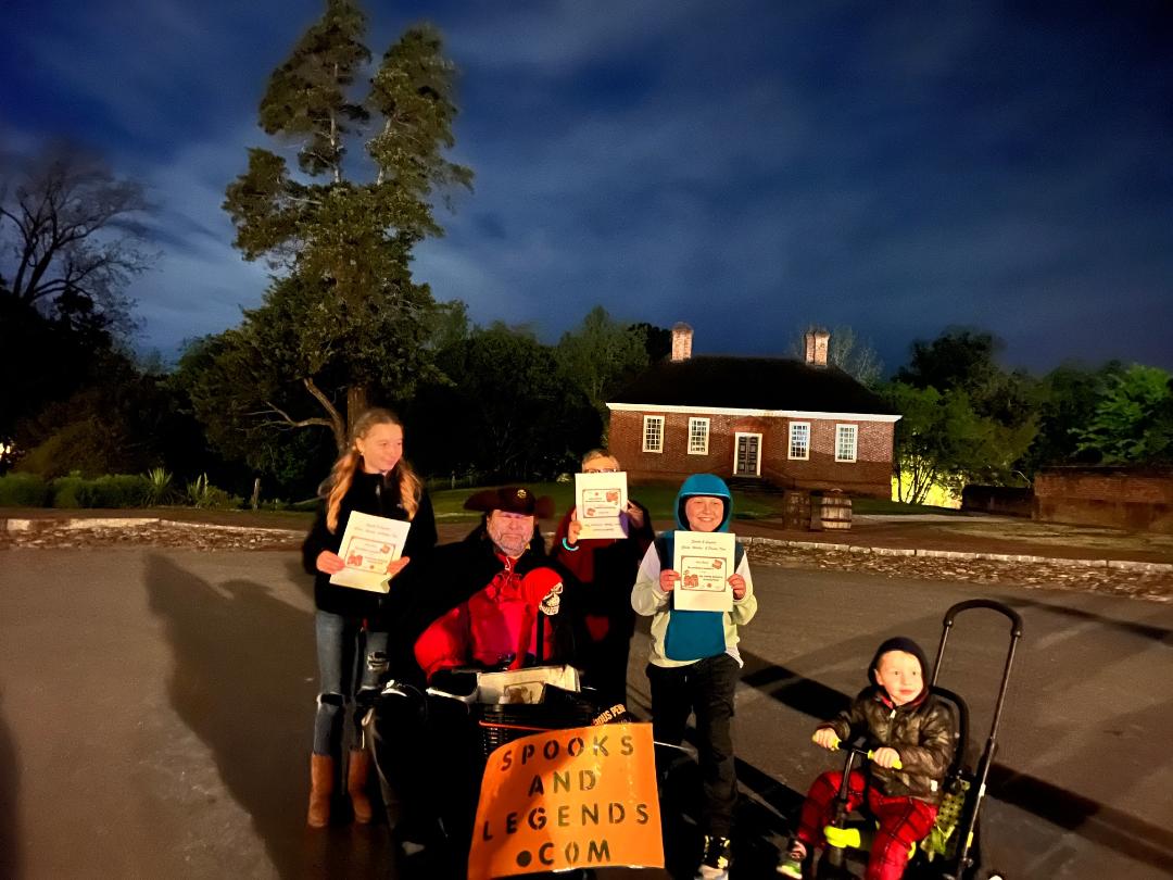 Group poses with signed items in front of a building at night. 