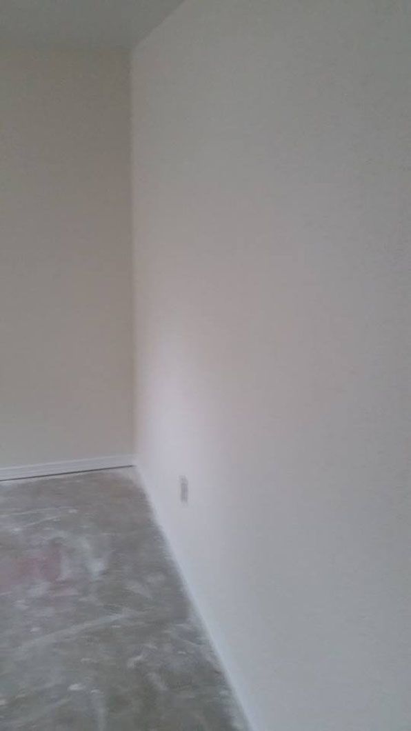 Empty room corner with white walls and a bare concrete floor.