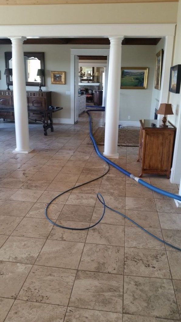 Living room with tiled floor, white columns, and blue cables running across the center