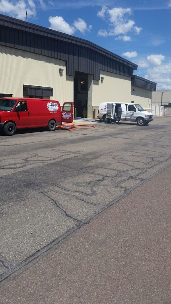 Red and white service vans parked outside a warehouse under a bright blue sky.