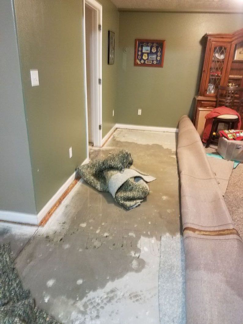 Living room with a rolled-up rug on the floor beside a couch and cabinet