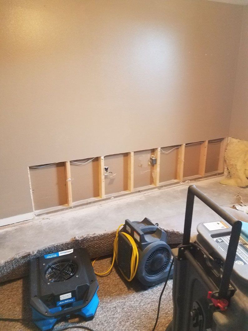 Partially demolished interior wall with exposed studs and tools on the floor during renovation