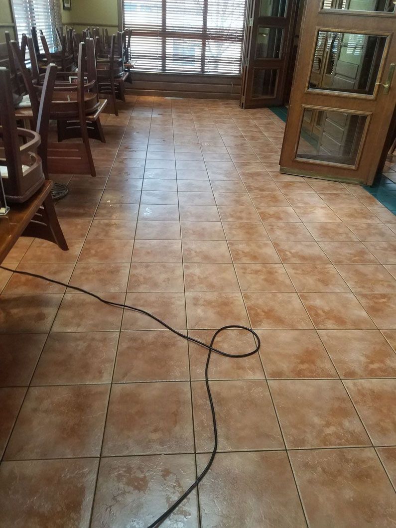 Empty room with tiled floor, chairs along the sides, and a cord lying across the center