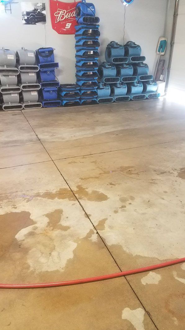 Garage floor with stacked blue and black equipment along the wall and a red cord across the foreground.
