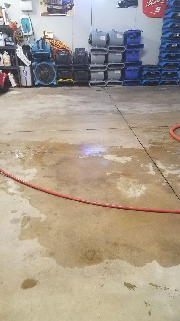 Concrete garage floor with a red hose and storage bins along the back wall