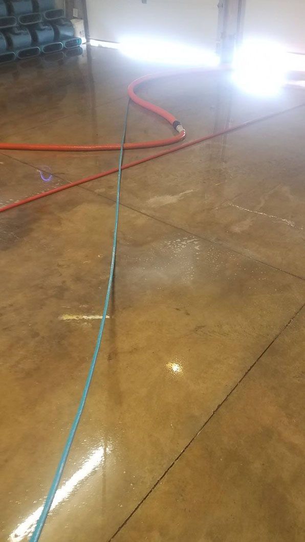 Red and blue cables cross a shiny tiled floor, with bright lights reflecting in the background.